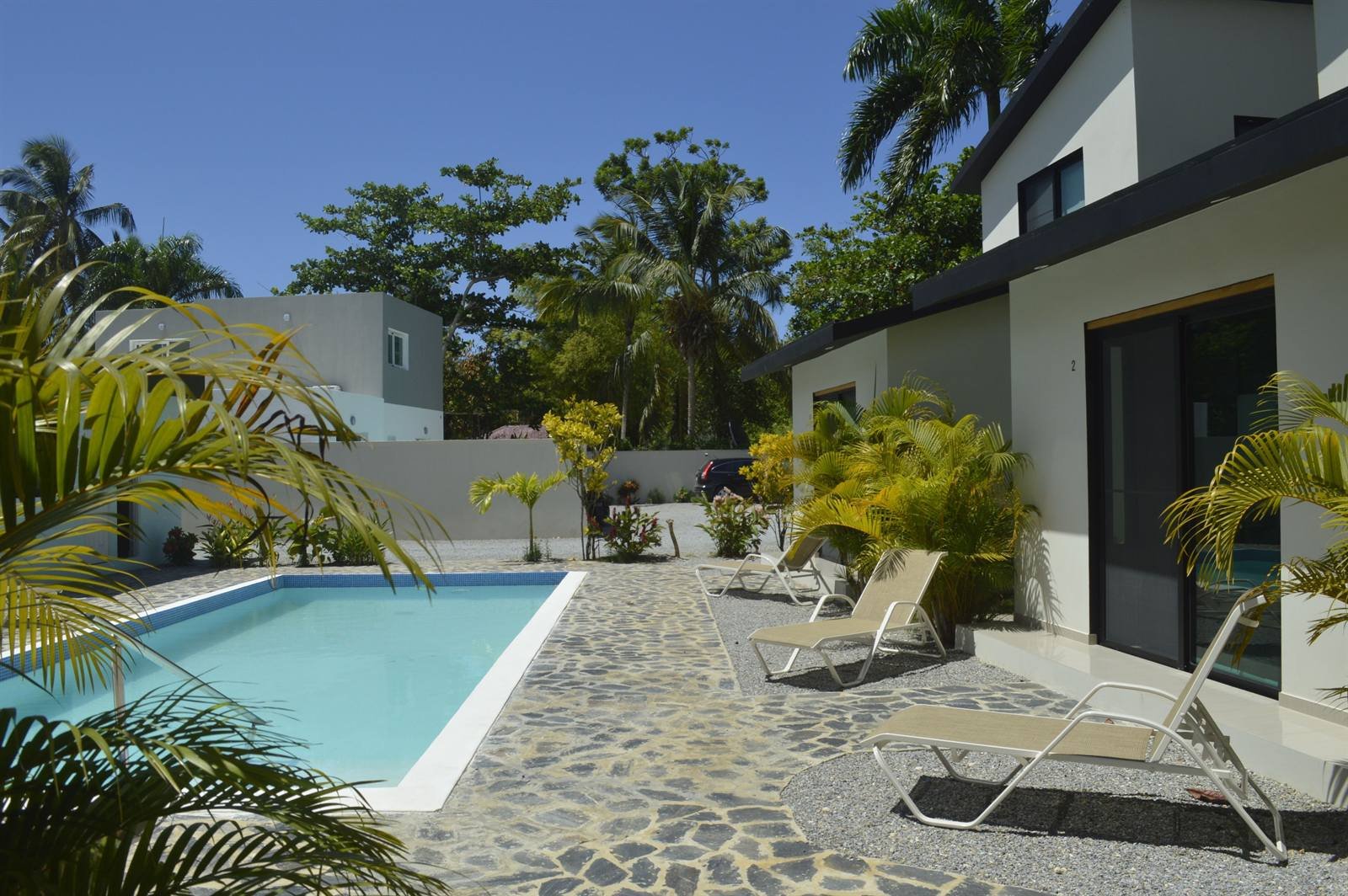 Residence Las Dos Palmas: stone pool deck with loungers and tropical plants